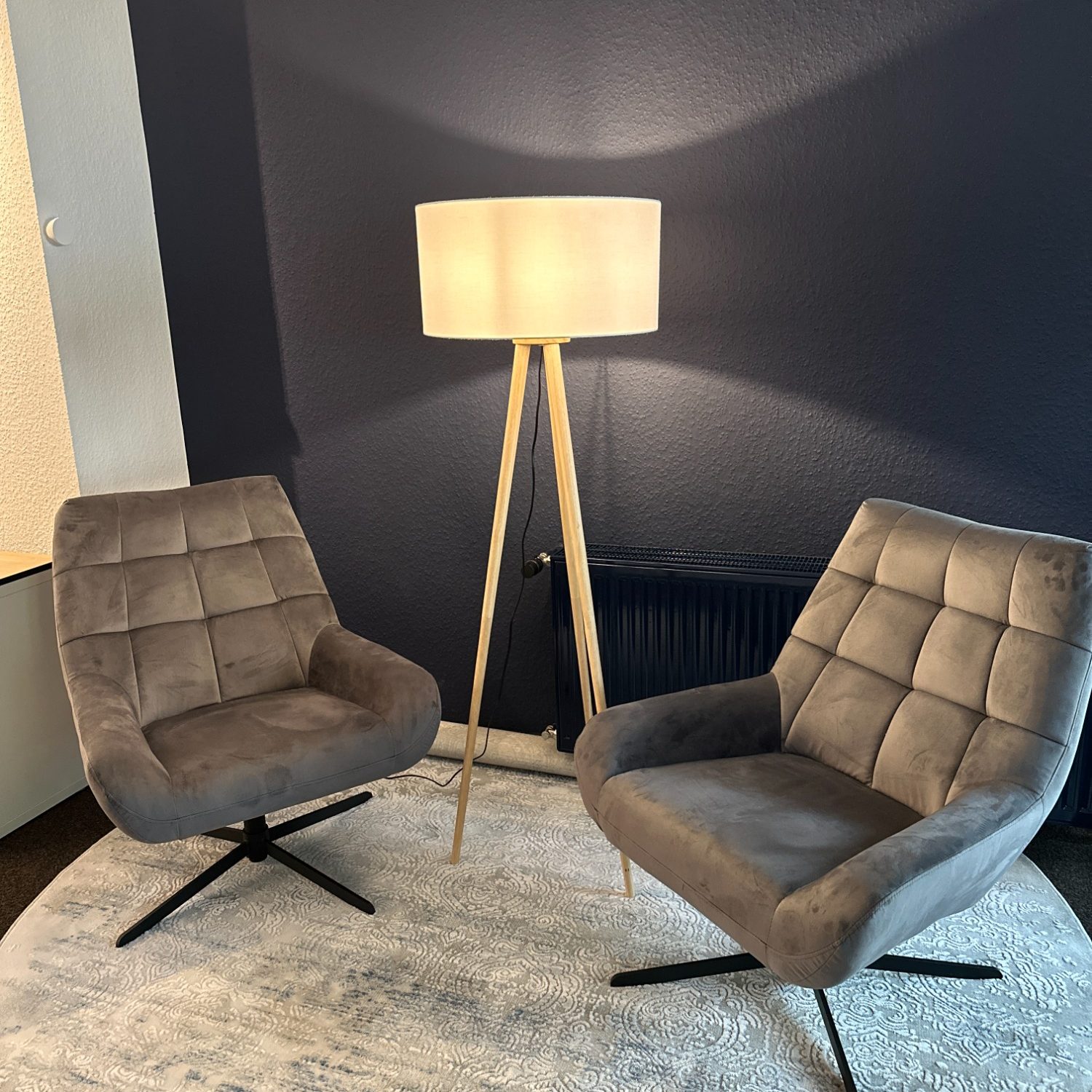 Zwei graue Stühle mit Lederbezug und eine Stehlampe in einem modernen Raum.