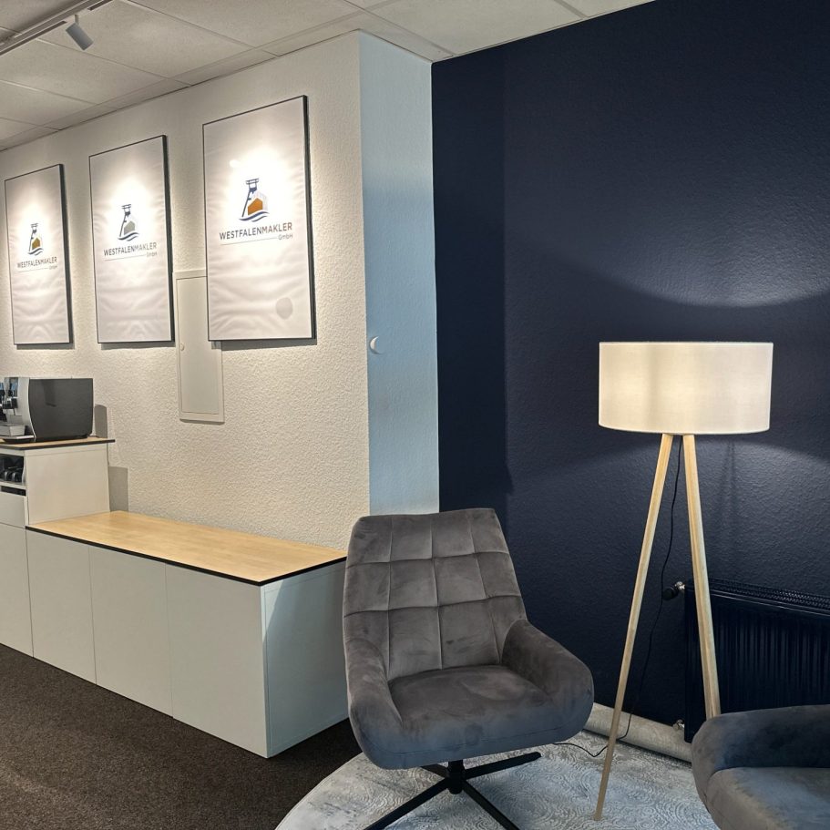 Moderner Innenraum mit zwei grauen Stühlen und einer Stehlampe vor einer blauen Wand.